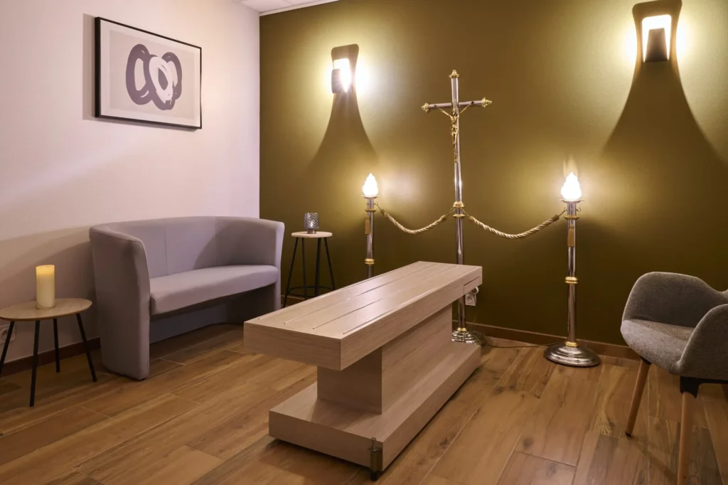 Salon funéraire de recueillement avec tréteau, canapé, bougies et croix pour hommage religieux