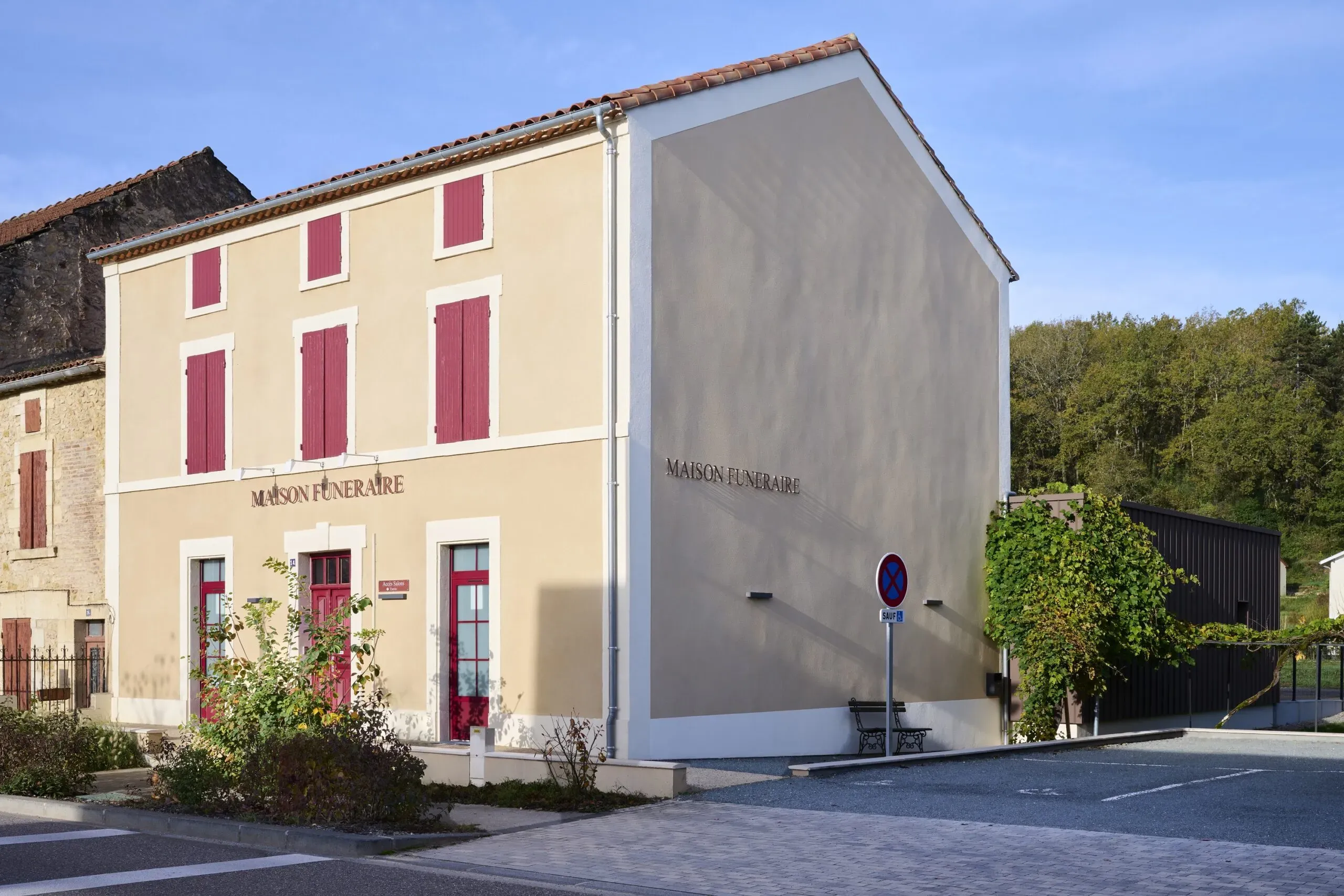 Bâtiment de la maison funéraire de tradition avec volets bordeaux et parking réservé